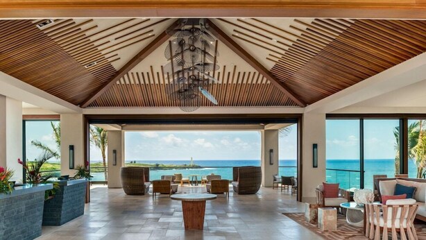 A spacious indoor area with a view of the ocean, featuring a wooden ceiling, comfortable seating, and a reception desk. - Timbers Kauai (Lihue)