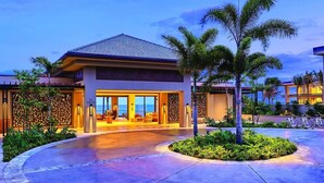 A modern hotel with a spacious lobby, large windows, and a well-maintained outdoor area with palm trees. - Timbers Kauai (Lihue)