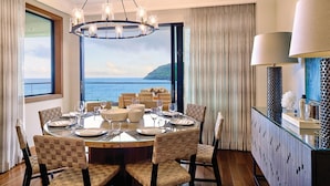 Un coin repas avec une table ronde, des chaises en osier et une vue sur la mer.