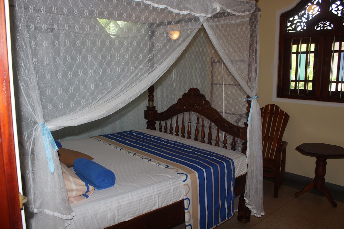 A bed with a canopy, a wooden headboard, and a blue and white striped bedspread.