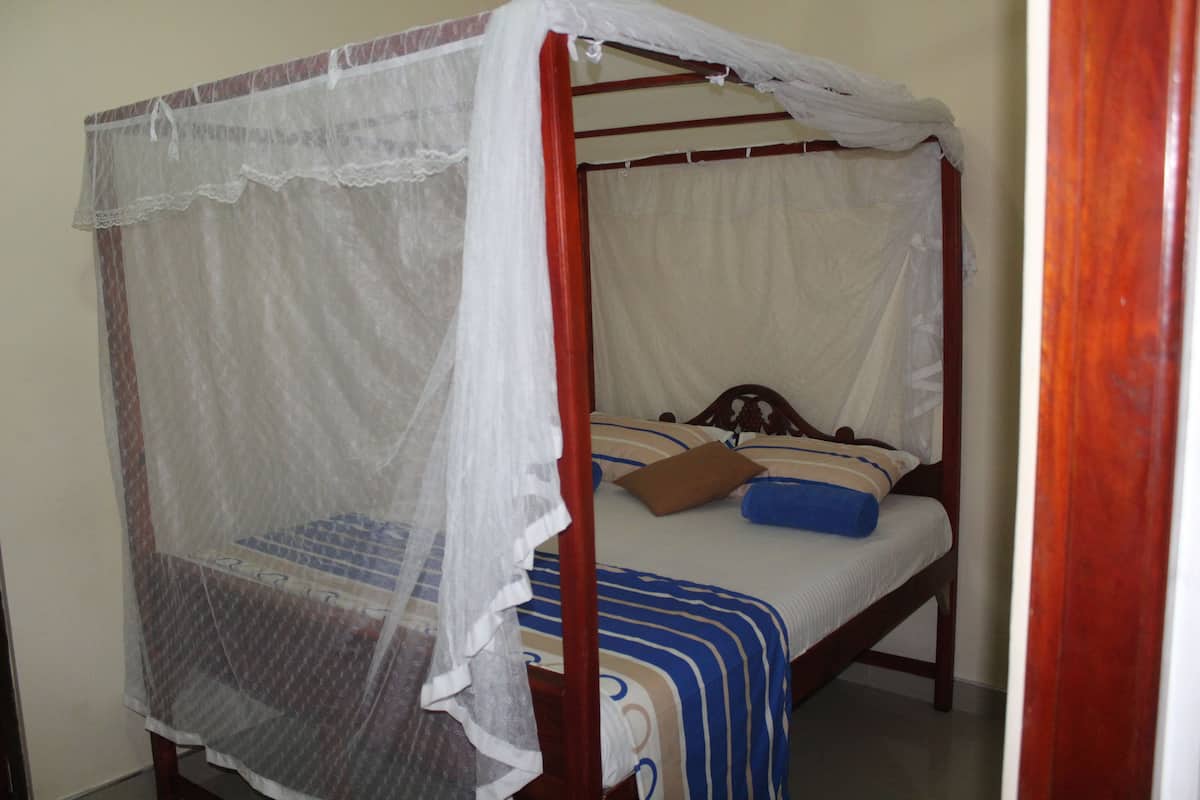 A four-poster bed with a canopy, a striped bedspread, and a blue pillow.
