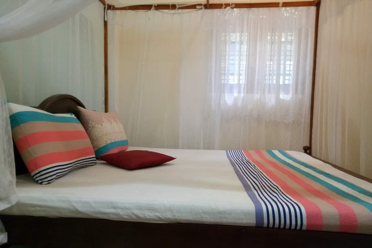 A bed with striped bedding, a canopy, and several pillows.