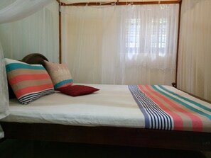 A bed with striped bedding, a canopy, and several pillows. - Tiny Royal Palace (Unawatuna)