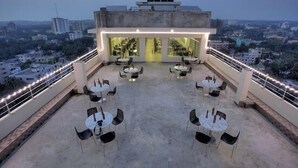 Une terrasse sur le toit, avec des tables et des chaises, un mur de verre et une vue sur la ville.