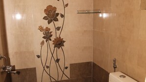 Baño con inodoro, ducha y un diseño de azulejos florales decorativos en la pared.