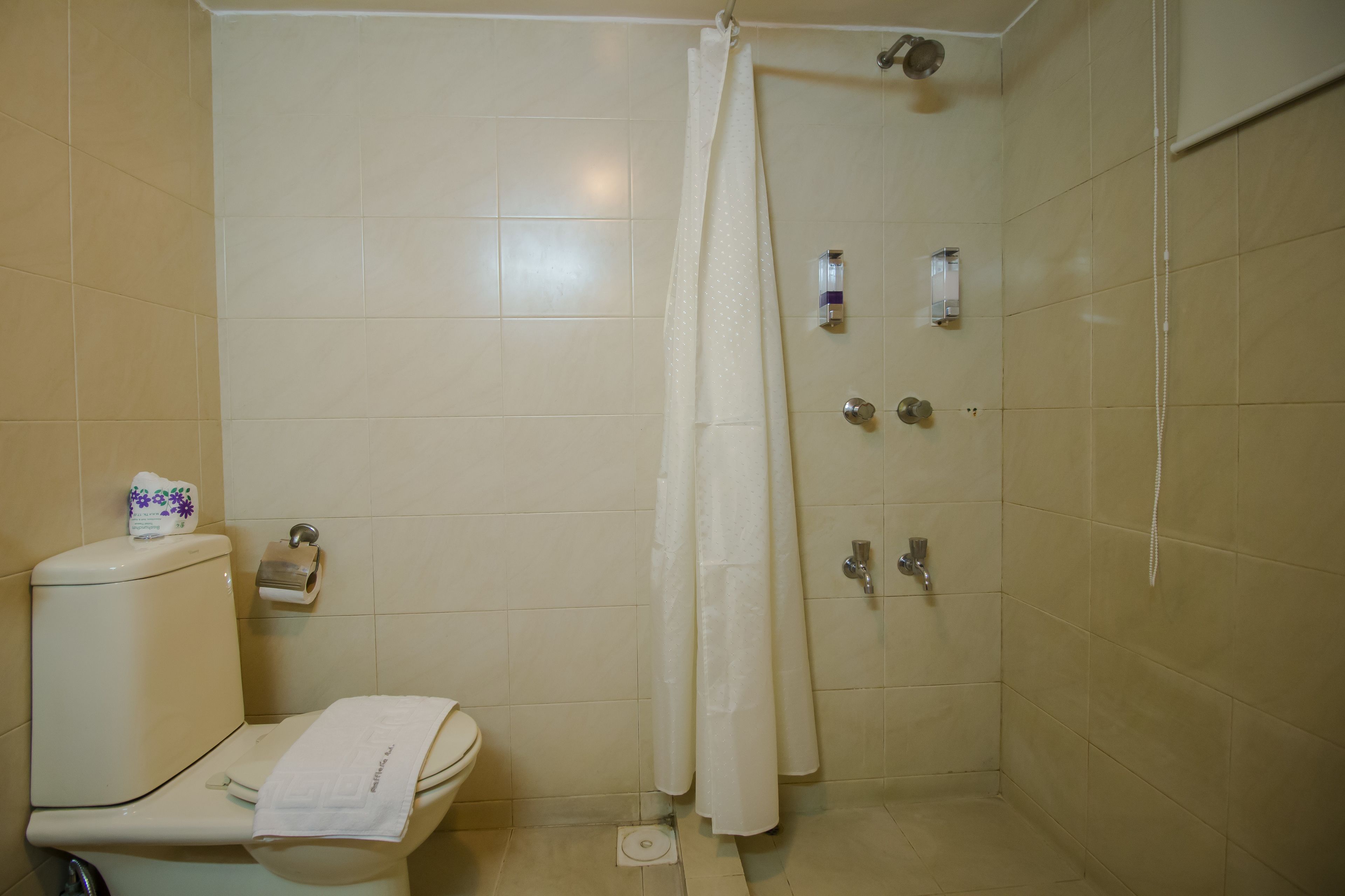 Un baño con inodoro, ducha con cortina y barra para toallas.