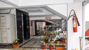 A reception area with a staircase, potted plants, a fire extinguisher, and a check-in counter. - Hotel Biswanath (Guwahati)
