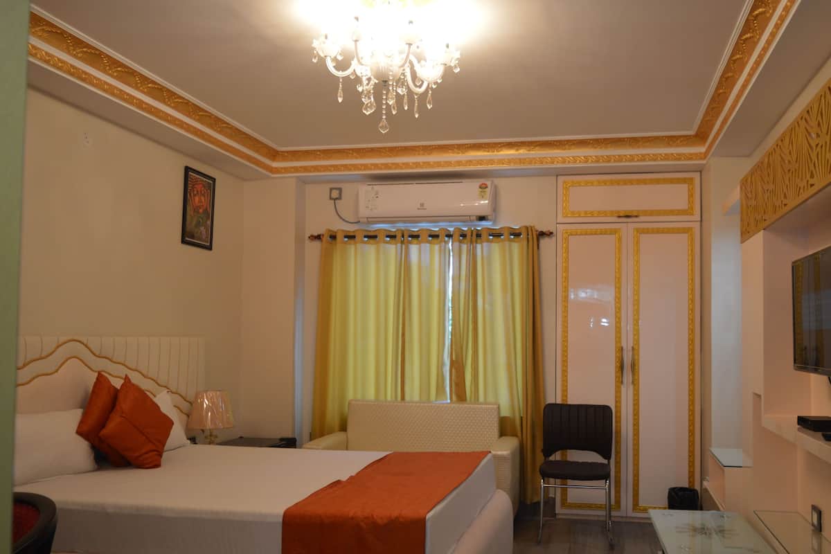 Ein Hotelzimmer mit Bett, Sessel, Schreibtisch und Fernseher.