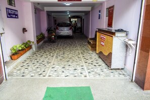 A reception area with a tiled floor, a reception desk, a parked car, and potted plants.