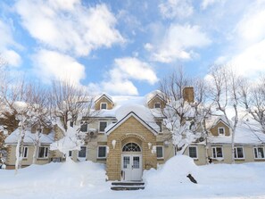 Een groot, meerhoog herenhuis met een symmetrische voorgevel, een centrale ingang met een decoratieve boog en een besneeuwde omgeving.