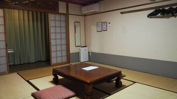 Une pièce de style japonais traditionnel, avec un sol recouvert de tatamis, une table en bois avec un coussin, un miroir et une horloge au mur.