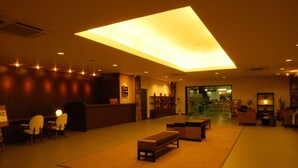 A hotel lobby with a reception desk, seating area, and a large skylight.