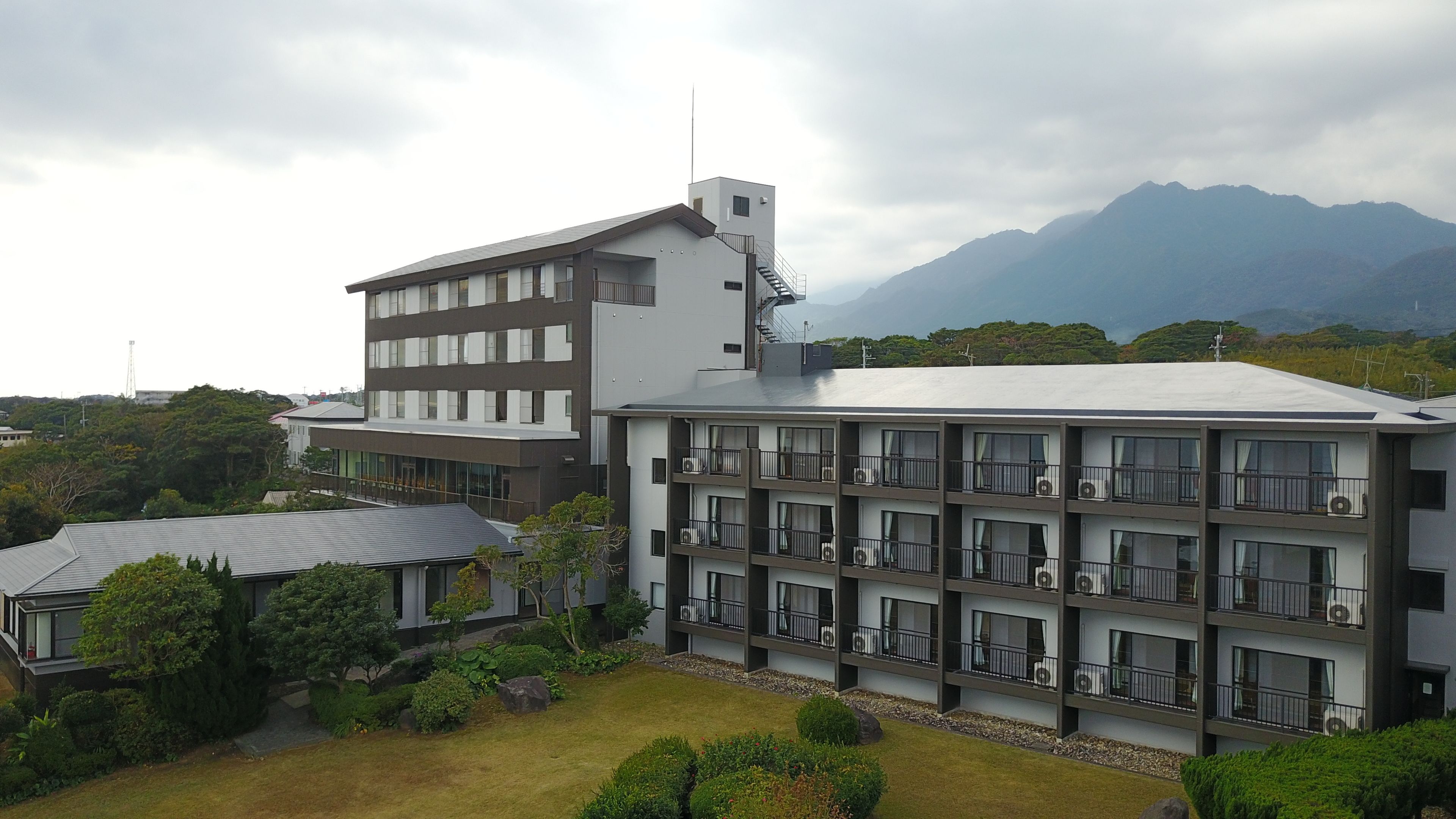 A multi-story hotel with a modern architectural design, featuring balconies and air conditioning units.