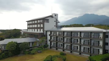 A multi-story hotel with a modern architectural design, featuring balconies and air conditioning units.