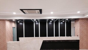 A reception area with a marble counter, black vertical panels, and a ceiling with recessed lighting. - Hotel Lakeview (Ahwa)