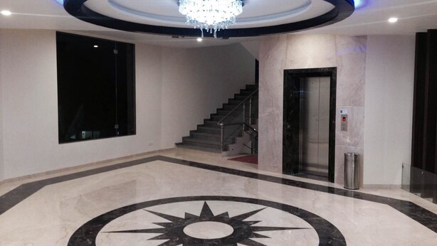 A lobby with a central sunburst floor design, a staircase, and a chandelier. - Hotel Lakeview (Ahwa)