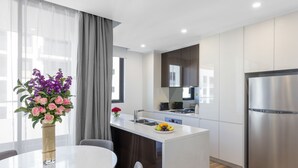 Una cuina moderna amb una illa central, electrodomèstics d'acer inoxidable i una zona de menjador amb un ram de flors.