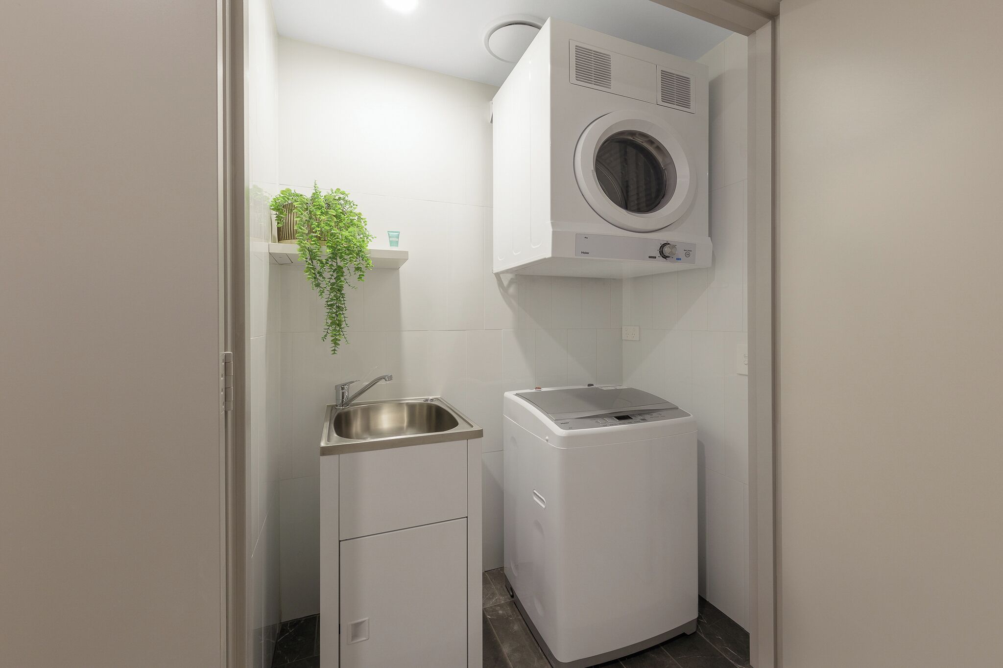 A compact laundry room with a washing machine, a sink, and a small cabinet.