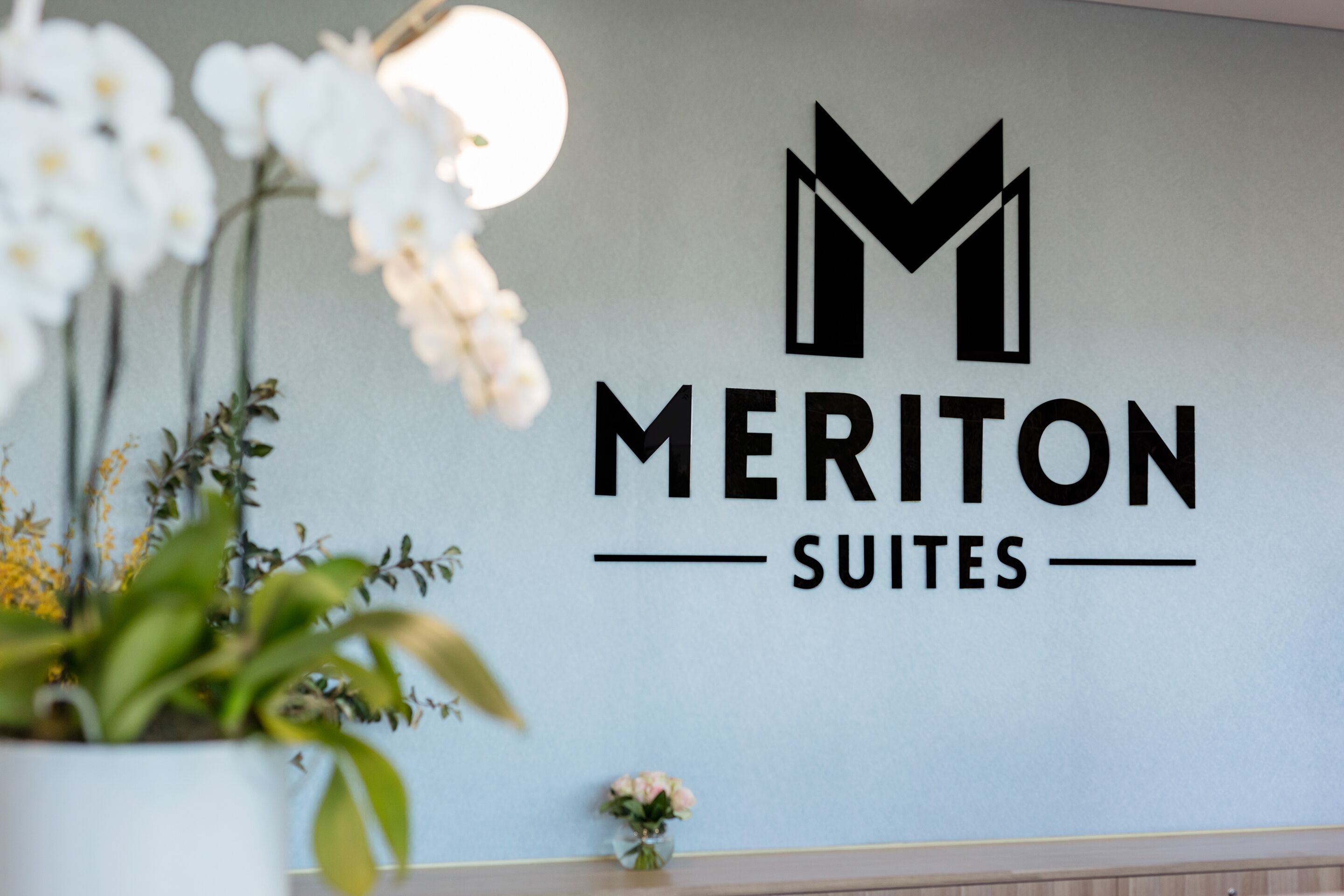 A wall with the text "MERITON SUITES" and a logo.