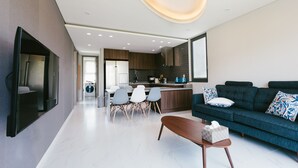 A modern living room with a sofa, coffee table, and dining area. - Jeju Daonjae (Seogwipo)