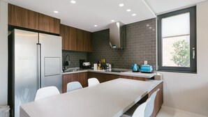 A modern kitchen with a built-in refrigerator, a large island with seating, and a window providing natural light. - Jeju Daonjae (Seogwipo)