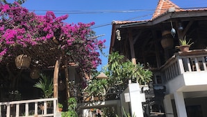 A traditional building with a tiled roof, a stone wall, and a pathway leading to a wooden door. - Padang Padang Breeze (Pecatu)