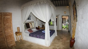 A bedroom with a four-poster bed, a wooden chair, and a vase with dried plants. - Padang Padang Breeze (Pecatu)