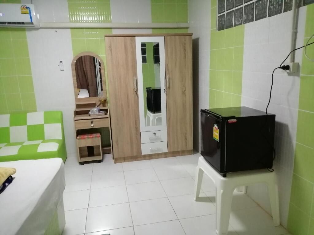 Una habitación con cama, armario, una mesita y refrigerador.