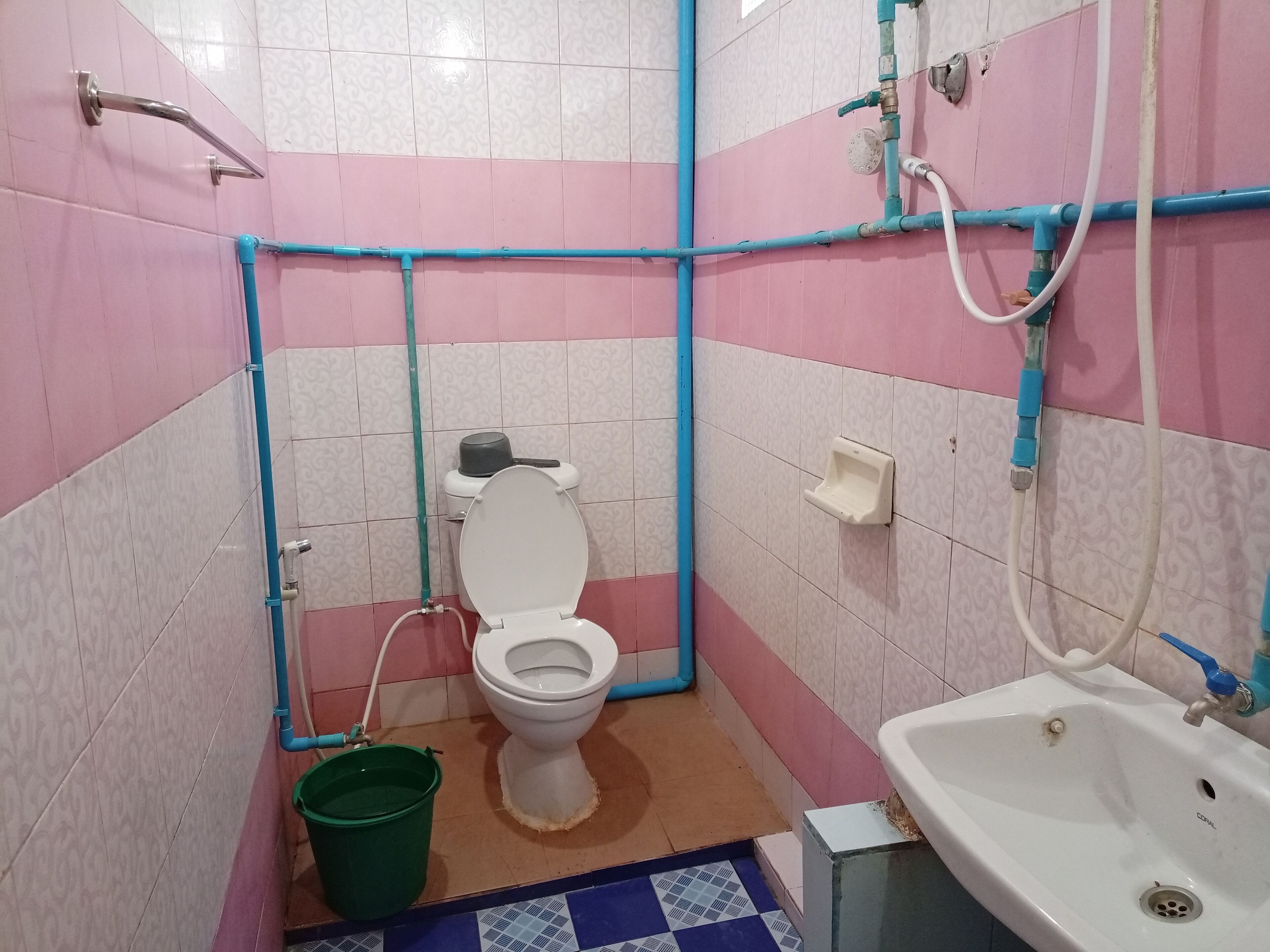 Et lille badeværelse med toilet, håndvask og en grøn balje.