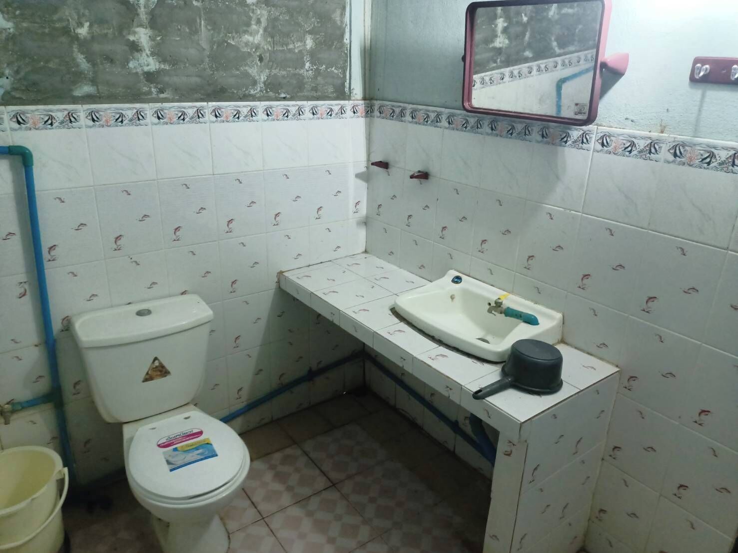 A small bathroom with a toilet, sink, and a mirror.