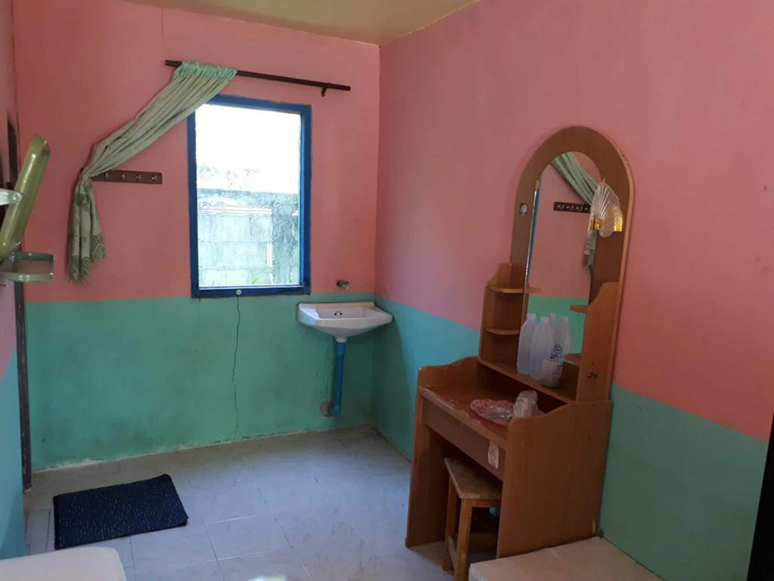 Een kleine badkamer met een wastafel, een spiegel en een raam.