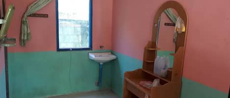 A small bathroom with a sink, a mirror, and a window.