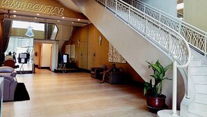 A hotel lobby with a staircase, seating area, and a reception desk. - Waterplace Residence (Surabaya)