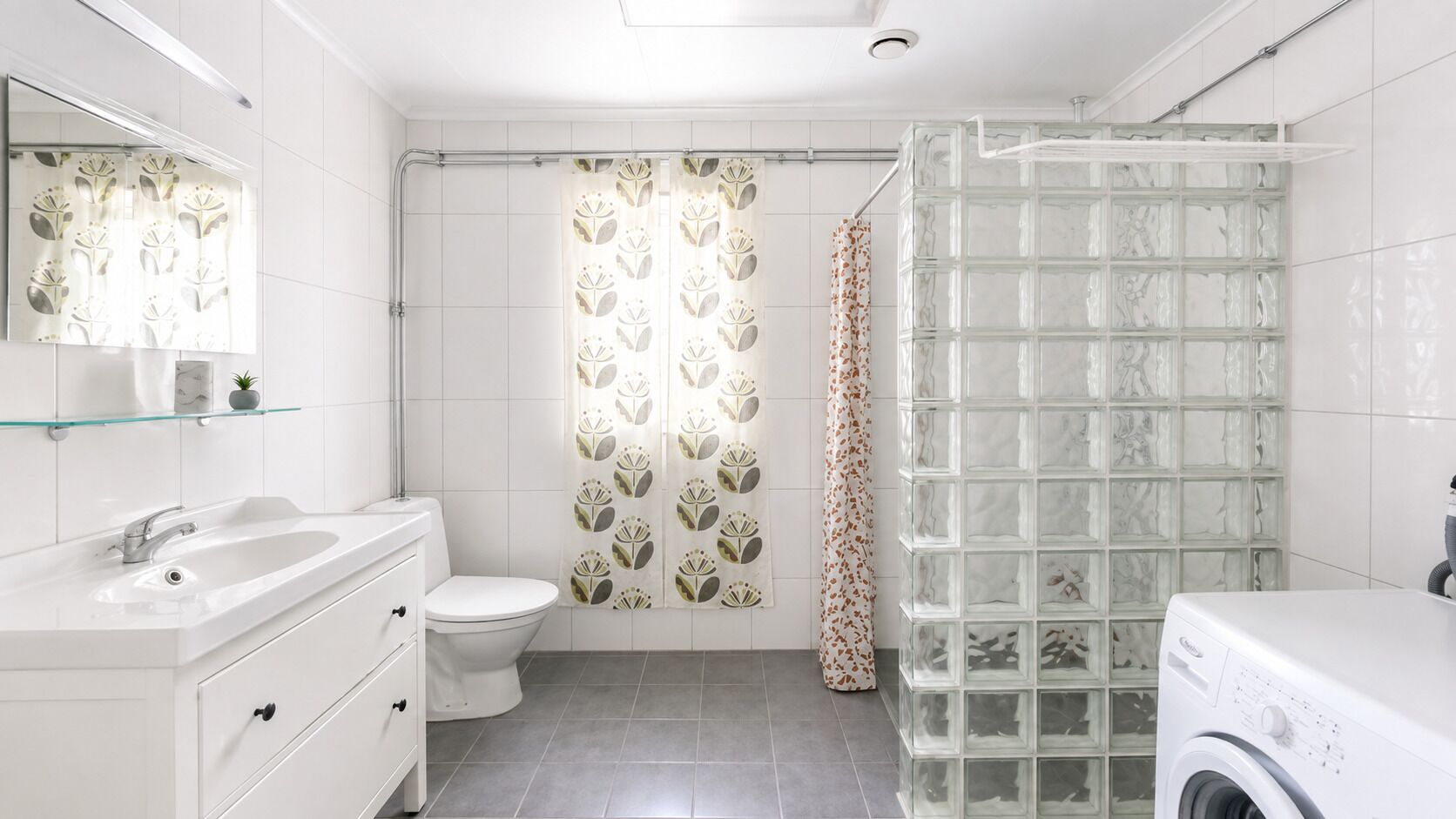 A modern bathroom with a glass shower enclosure, a toilet, a sink, and a washing machine.