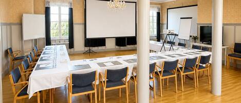 A conference room with a long table, chairs, a projector screen, and a whiteboard.