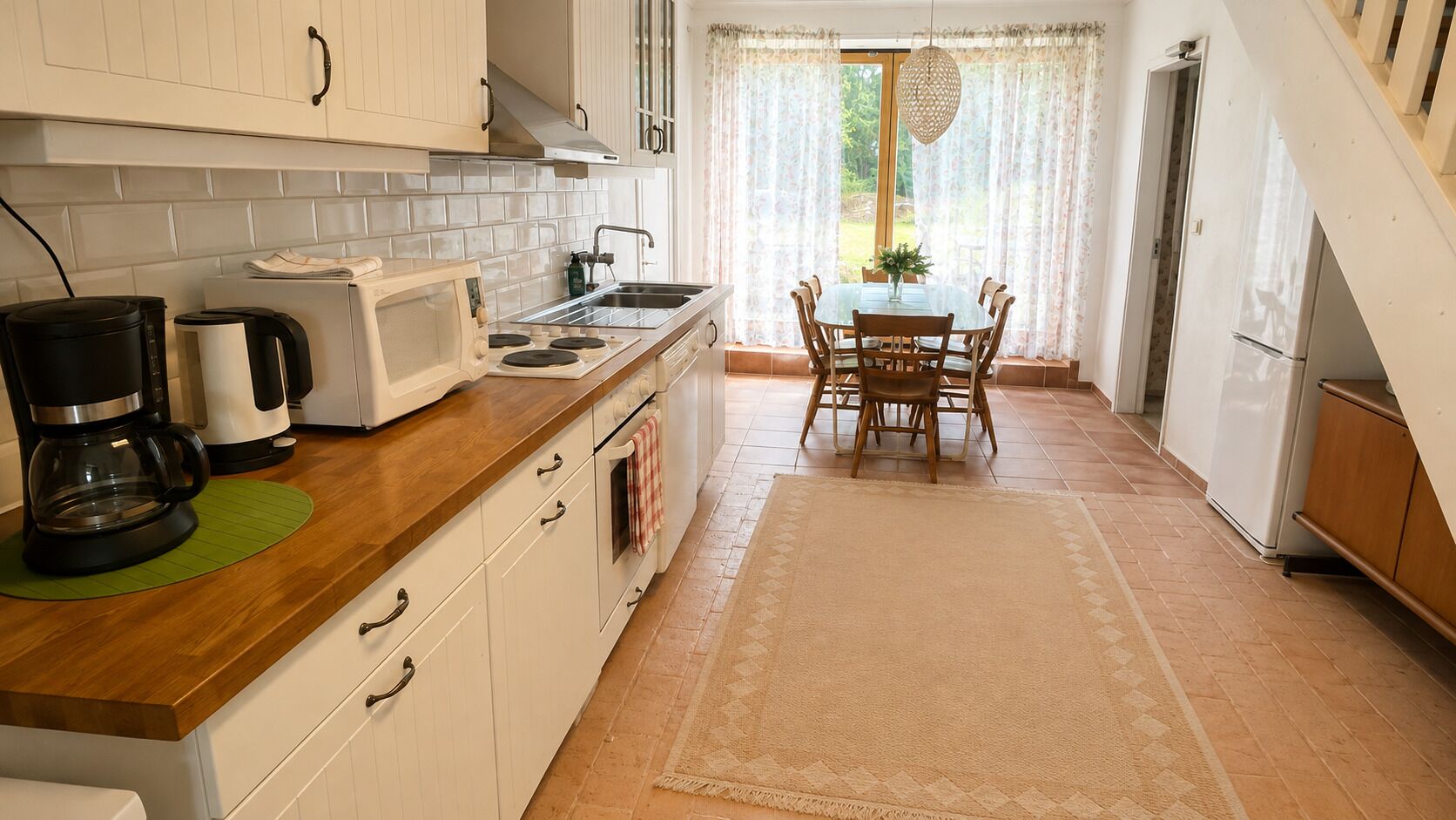 A kitchen with a dining area, a coffee maker, a microwave, and a refrigerator.