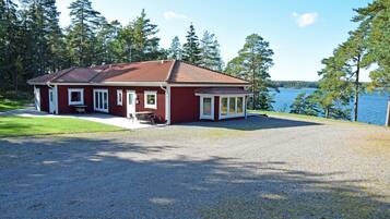 Une maison rouge avec une allée en gravier et une vue sur un lac.