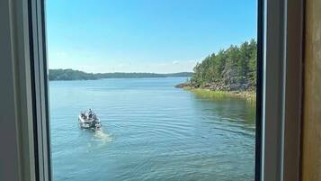Vista a través de una ventana de un lago con un barco y una orilla arbolada.