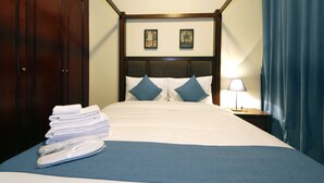 A hotel room with a neatly made bed, a stack of towels, a nightstand with a lamp, and two framed pictures on the wall. - Piks Key- Al Hamra Village (Ras Al Khaimah)