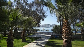A stone pathway leading to a body of water with palm trees and grass on either side. - Halic Park Hotel (Ayvalik)