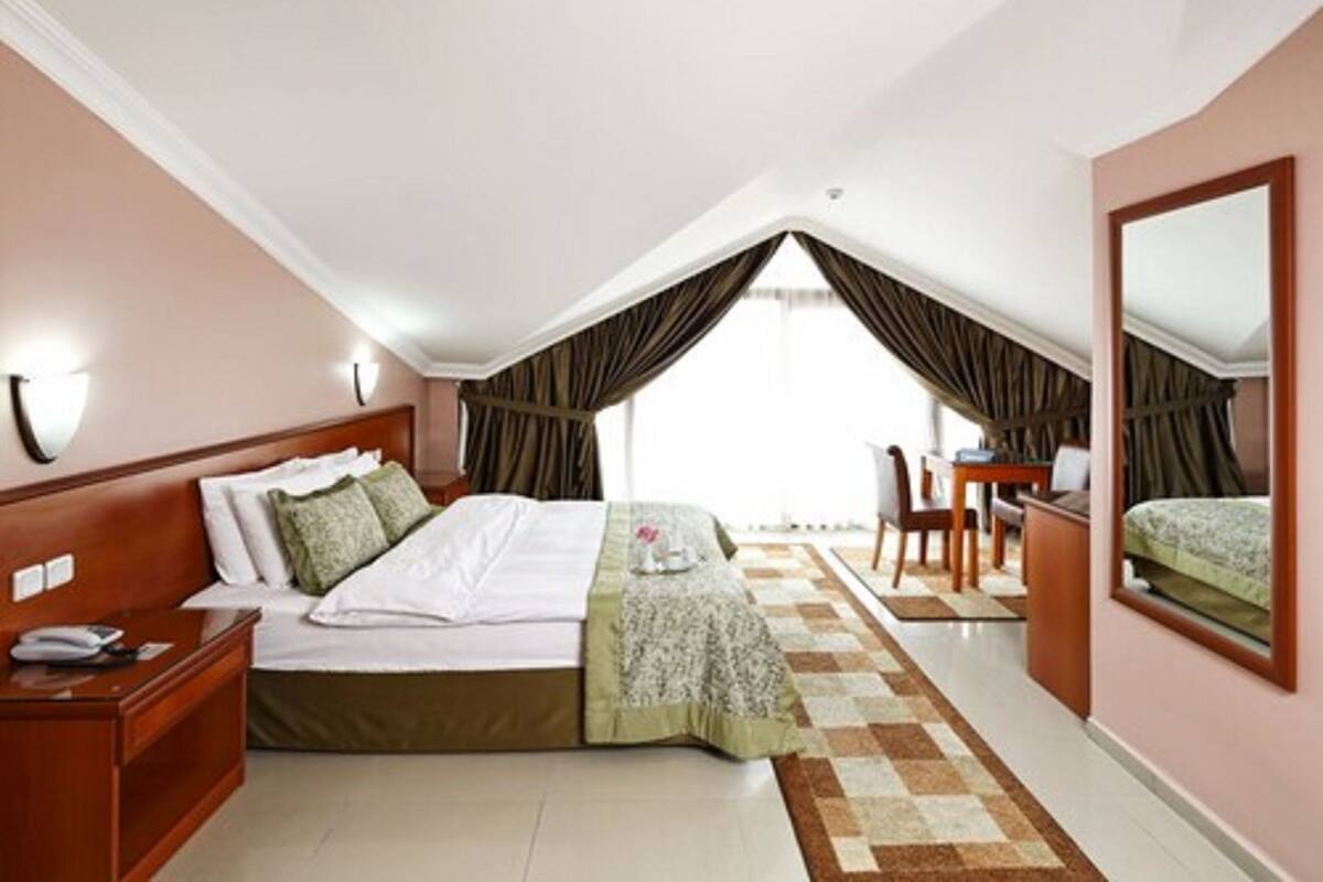 A bedroom with a bed, bedside table, chair, and a desk.