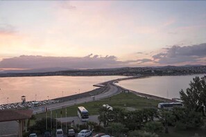 A coastal view with a marina, parked vehicles, and a road curving along the water. - Halic Park Hotel (Ayvalik)