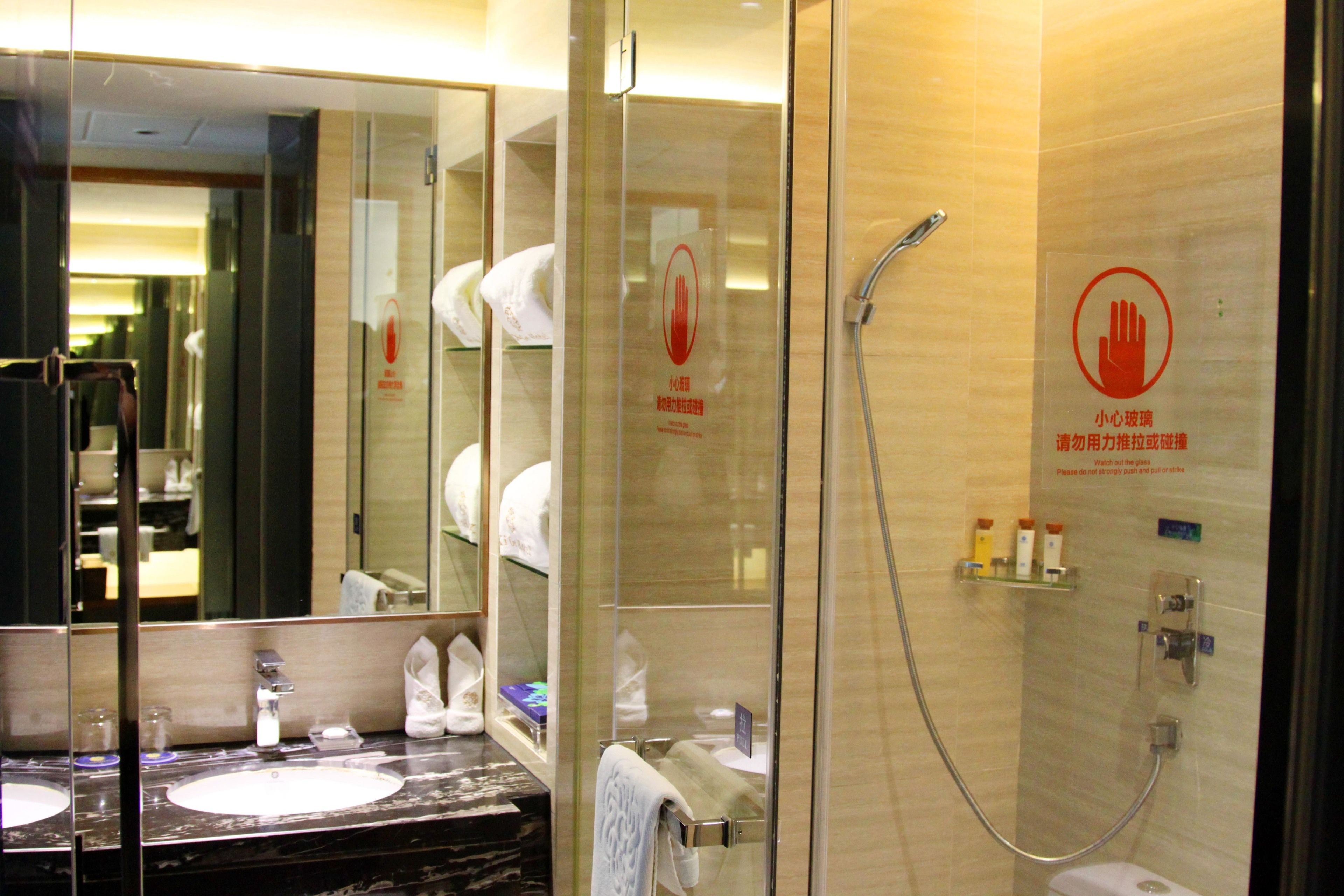 A modern bathroom with a glass-enclosed shower, a marble sink, and a large mirror.