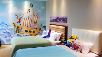 Une chambre d’hôtel avec deux lits, une fresque représentant un navire de pirates et un tableau représentant un paysage urbain accroché au mur.