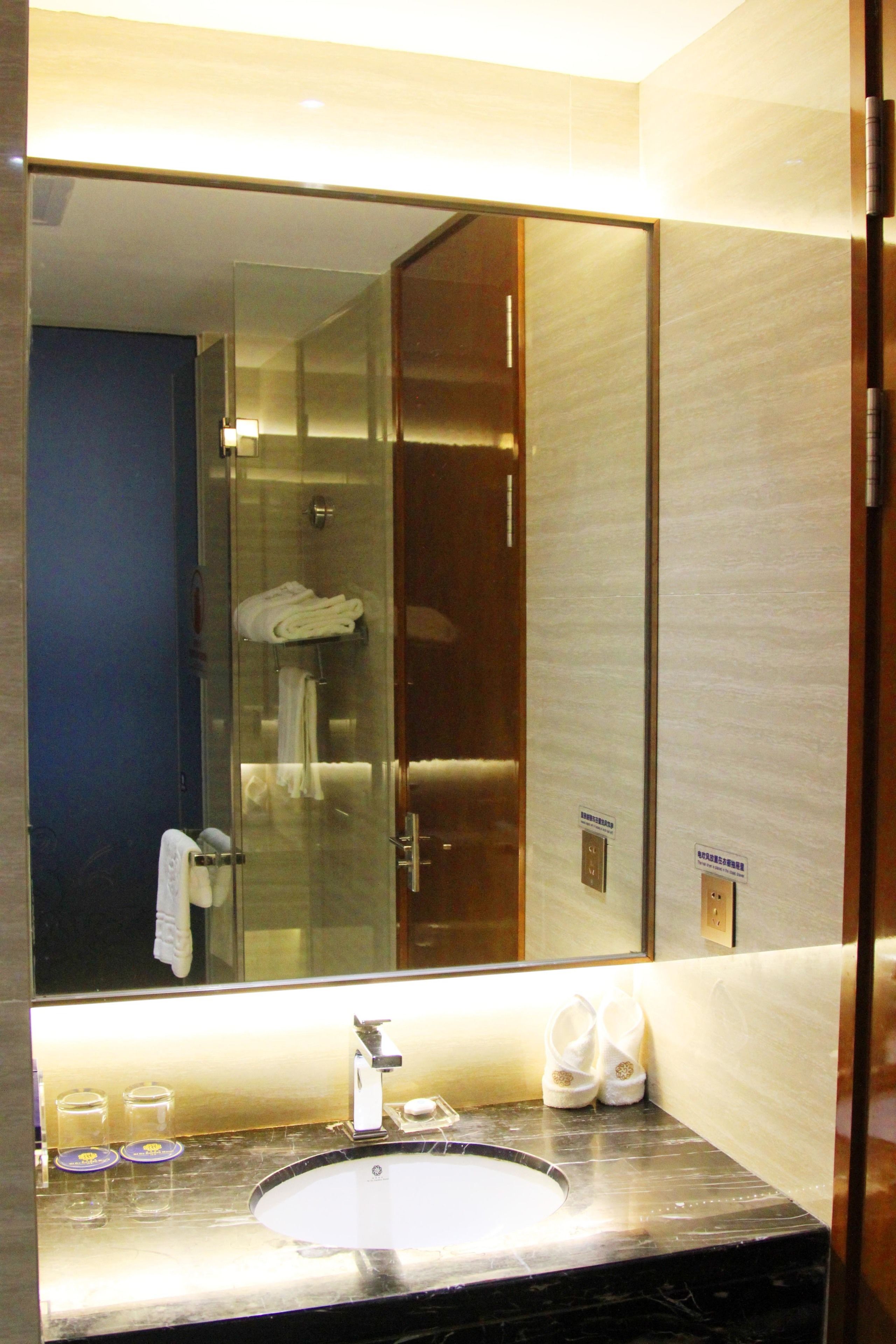 A bathroom with a large mirror, a sink, and a glass shower enclosure.