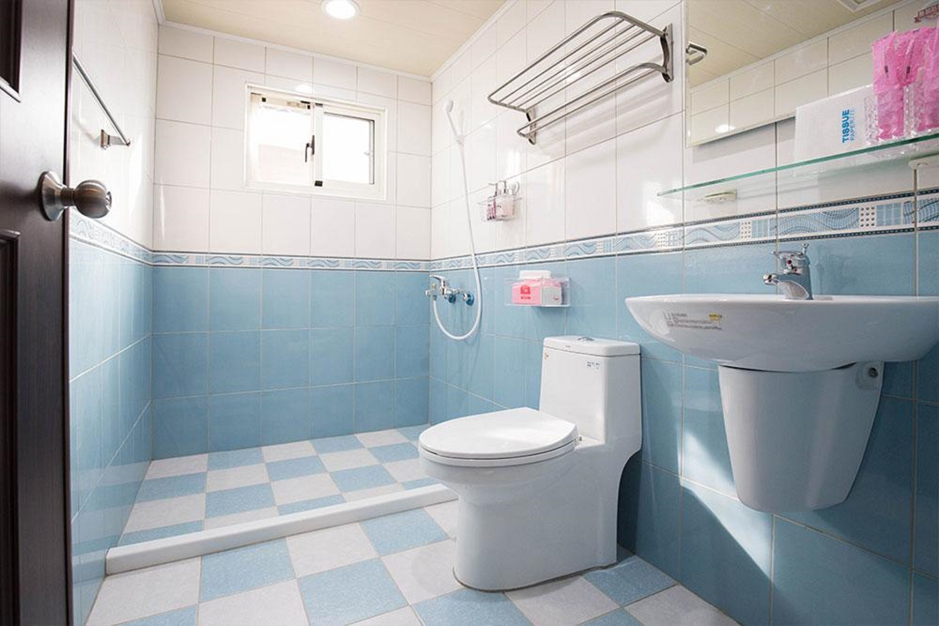 A bathroom with a checkered floor, a toilet, a sink, and a window.