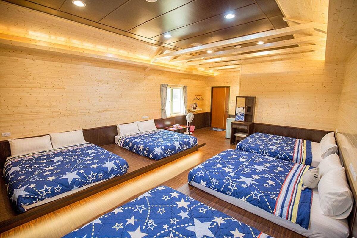 Una habitación con tres camas, paredes de madera e iluminación empotrada en el techo.
