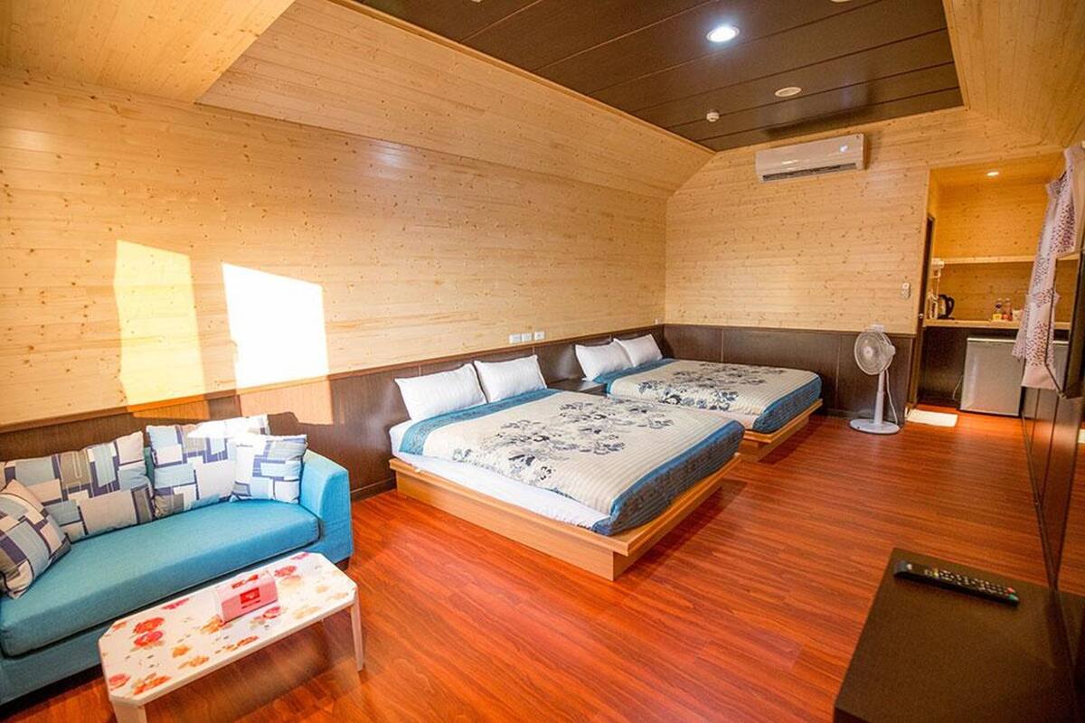 Una habitación con dos camas, un sofá, una mesita y un ventilador.