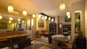 A cozy restaurant with a dining area, a bar, and a seating area with sofas and a fireplace. - Grand Sehati & Spa Ubud (Ubud)