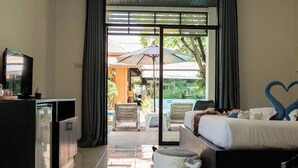 A hotel room with a bed, a TV, a desk, and a view of the outside.